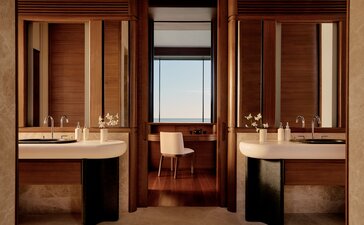 Bathroom at Amanvari with dual vanities, warm wood cabinetry and ocean views through central doorway.