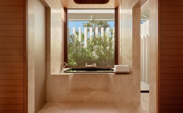 Bathroom at Amanvari with terracotta walls, wooden shutters, and estuary views.