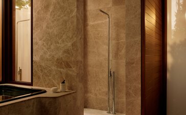 Bathroom at Amanvari with travertine walls and glass shower enclosure.
