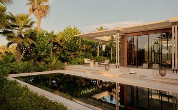 Estuary Casita at Amanvari resort with reflecting pool and palm trees at dusk.