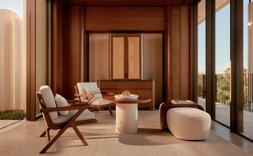 Amanvari casita living area with wooden furnishings and desert horizon view through floor-to-ceiling windows.