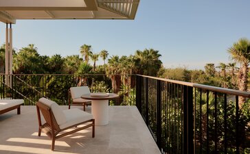 Horizon Casita terrace at Amanvari with lounge chair overlooking desert landscape and palm trees at sunset.