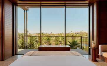 Bedroom at Amanvari with expansive windows overlooking Mexican landscape and desert vegetation.