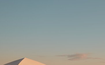 Two sun loungers and parasol on Amanvari's beach at sunset.