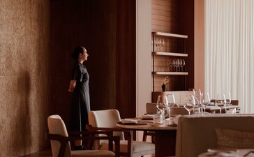 Warm-toned study at Amanvari with wooden furniture, shelving, and desk by soft lighting.