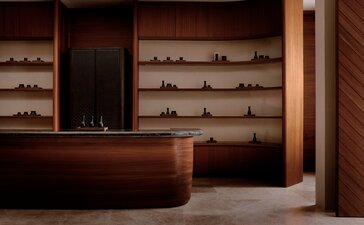 Amanvari spa entrance with wooden reception desk and shelving displaying wellness products.
