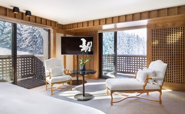 Chambre Mélézin bedroom at Aman Le Mélézin with wooden panelling, alpine views, and contemporary furnishings.