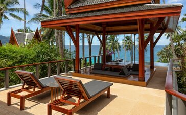 Ocean-view pool pavilion at Amanpuri with wooden loungers and ocean beyond.