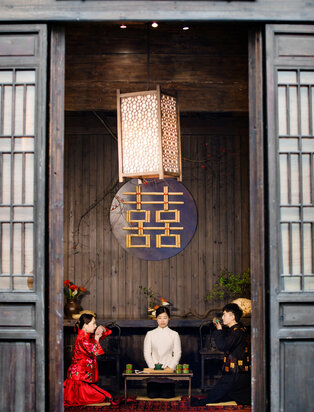 Three people seated at a wooden table beneath a traditional doorway at Amanfayun.
