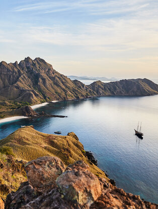 Sailing yacht anchored in turquoise waters beneath volcanic peaks at Amandira.