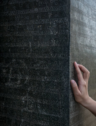 Hand touching textured concrete wall at Amanoi