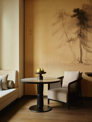 Detalhe da Junior Suite na Aman New York com assentos junto à janela, mesa lateral e arte mural minimalista.