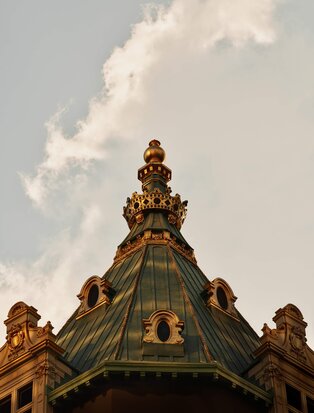 Golden pagoda spire with ornate details against cloudy sky at Aman New York.
