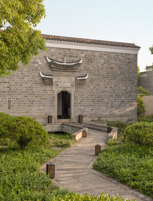 Stone pavilion at Amanyangyun with traditional curved roof and manicured gardens in China.