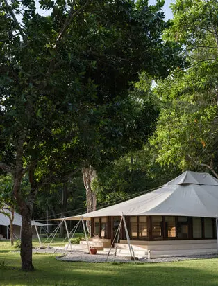 Jungle tent accommodation at Amanwana surrounded by lush trees and manicured lawns in Indonesia.