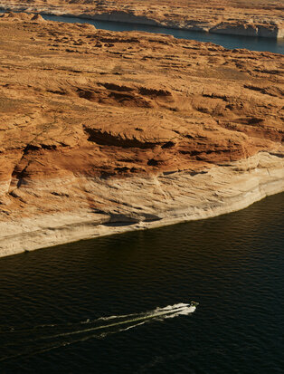Aerial view of a private aircraft flying over red rock formations and water at Amangiri resort.