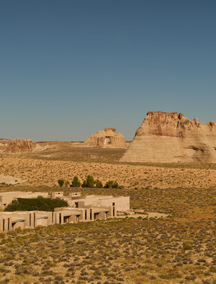 Amangiri's expansive desert landscape with terracotta rock formations and poolside loungers in the foreground.