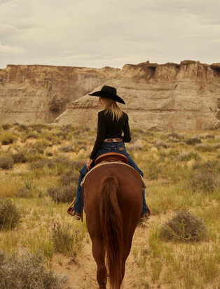 Rider on horseback across desert terrain at Amangiri resort.