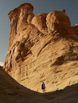 Climber ascending via ferrata route on towering sandstone formation at Amangiri resort.