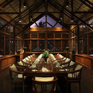 Amandari villa with illuminated terrace overlooking a still pool at dusk, surrounded by tropical trees.