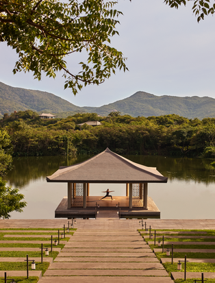 Wooden yoga pavilion at Amanoi extending over a tranquil river, surrounded by verdant Vietnamese landscape.