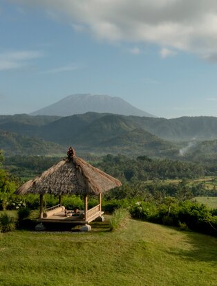Balinese temple pavilion framed by verdant rice terraces and Mount Agung at Amankila.