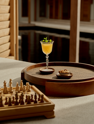 Cocktail with yellow drink and garnish on table at Amanyara bar, with chess set nearby.