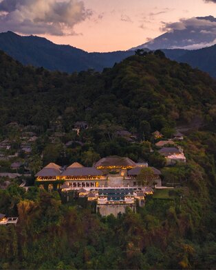 Amankila aerial view at sunset with mountain and beach backdrop, Bali.
