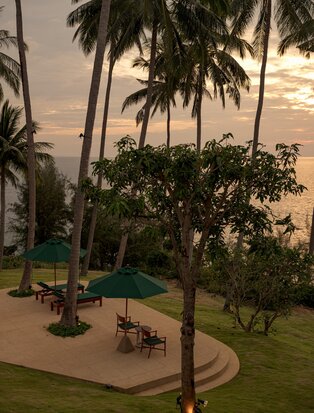 Amanpuri Resort in Thailand: eight-bedroom ocean villa with manicured gardens and palm trees at dusk.