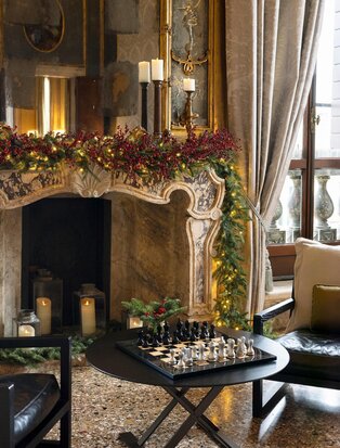 Tiepolo Room fireplace at Aman Venice adorned with festive garland and candles during Christmas.