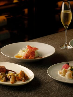 Festive dinner at Aman Tokyo with plated dishes and champagne on dark table.