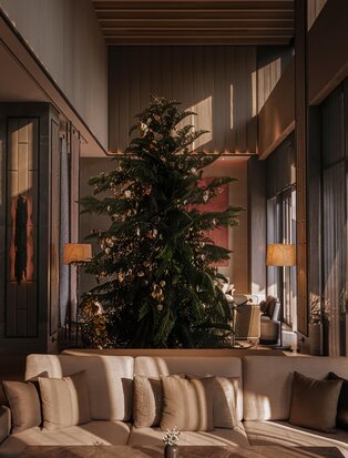 Decorated Christmas tree in the lobby at Aman Nai Lert Bangkok, with warm lighting and seating below.