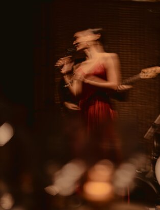 Performer in red costume mid-motion during F&amp;B lounge performance at Aman Nai Lert Bangkok.