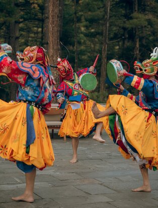 Performers in traditional Bhutanese dress dance on a courtyard terrace at Amankora Thimphu Lodge.