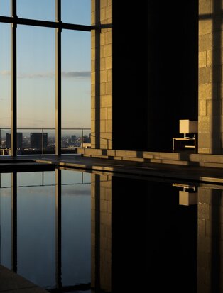 Serene spa pool at Aman Tokyo reflecting the city skyline at dusk through floor-to-ceiling windows.