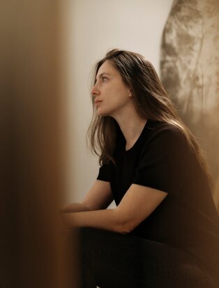 Studio portrait of Despina Flessa at Amanzoe, Greece, wearing a black shirt against a neutral backdrop.