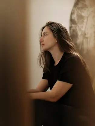 Studio portrait of Despina Flessa at Amanzoe, Greece, wearing a black shirt against a neutral backdrop.