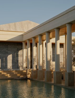 Amanzoe resort's columned architecture reflected in still water at dusk, Greece.