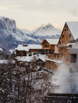 Aman Rosa Alpina exterior with snow-covered peaks and alpine architecture in winter.