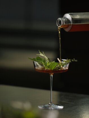 Cocktail being poured into a glass with fresh mint at Aman Tokyo's bar.