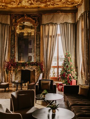 Tiepolo Room at Aman Venice adorned with festive Christmas decorations, featuring ornate gold-framed mirrors and elegant drapery.