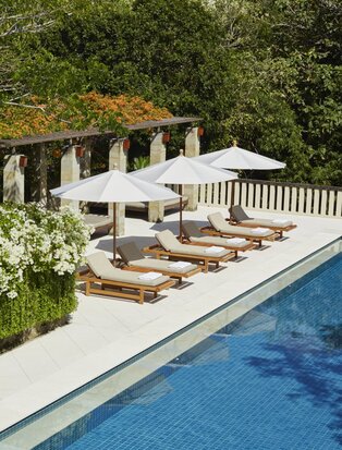 Six-bedroom villa swimming pool with stone archway and loungers at Aman Villas at Nusa Dua, Indonesia.