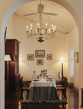 Chef's table set for dining beneath a chandelier in an arched stone alcove at Amangalla, Sri Lanka.