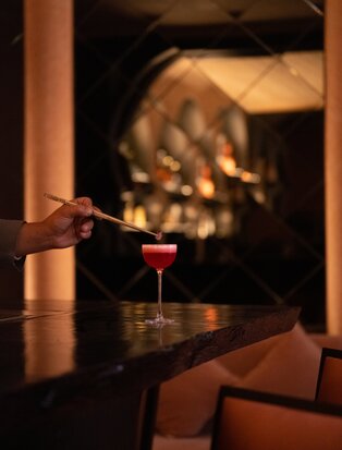 Cocktail being prepared at Arva Bar, Amanjena, Morocco, with candlelit ambiance.