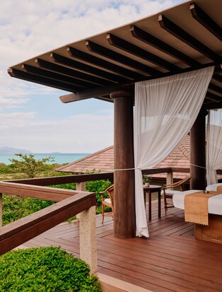 Spa massage room at Amanpulo with wooden pergola, flowing curtains and views across Philippine landscape.