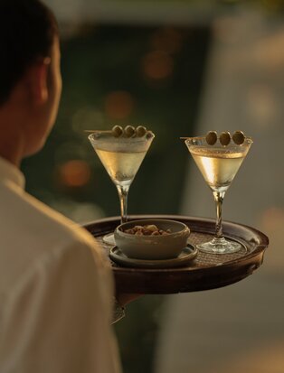 Server holding tray with two dirty martinis at Amantaka's bar in Laos.