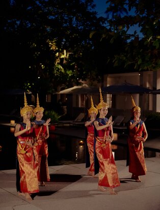 Monks in saffron robes light floating candles by the pool at Amantaka during Loy Kratong celebration.