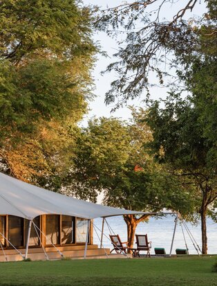 Ocean Tent accommodation at Amanwana, Indonesia, with open-sided pavilion beneath towering trees.