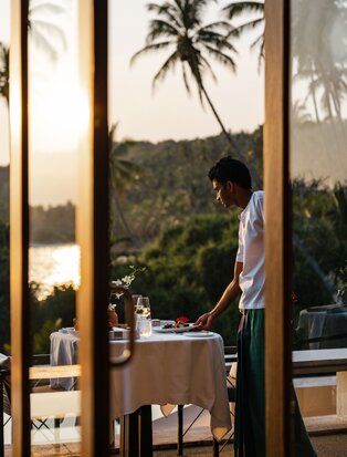 Dining terrace at Amanwella overlooking tropical landscape at dusk.