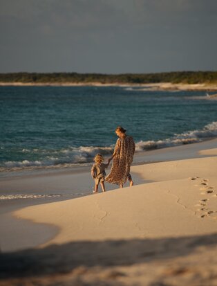 Family wading in turquoise waters at Amanyara's beach, Turks and Caicos.